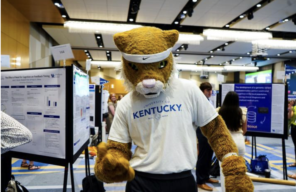 UK Wildcat mascot posing in front of research posters at the 17th Showcase of Undergraduate Research