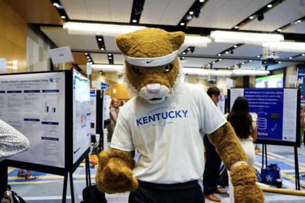 UK Wildcat mascot posing in front of research posters at the 17th Showcase of Undergraduate Research