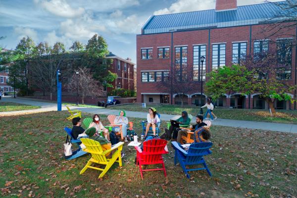 Students sitting in Adirondack chairs in a circle, talking