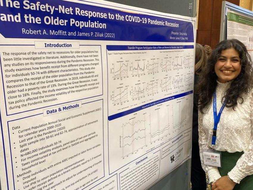 Shria Holla smiling standing next to her research poster