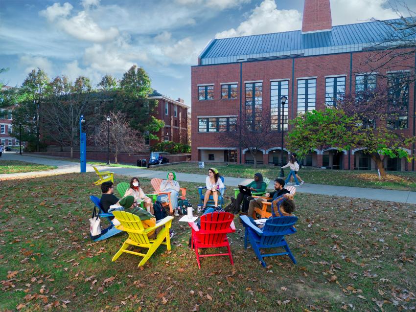 Students sitting in Adirondack chairs in a circle, talking