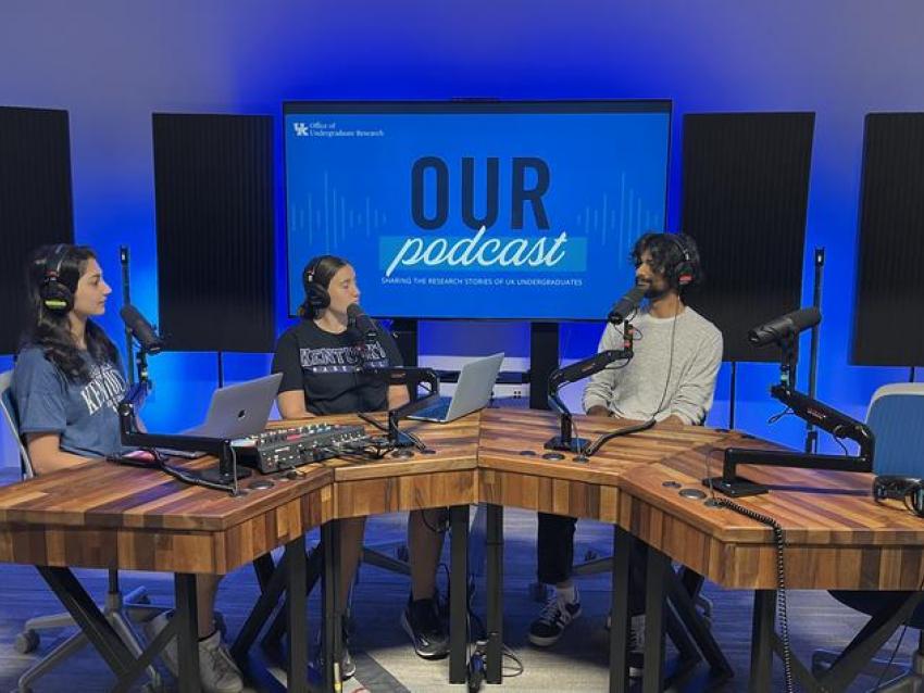 Undergraduate Research Ambassador's Sarisha Lohano and Hannah Allen interviewing UK undergraduate student Abdallah Sher on the OUR Podcast in a recording room in front of a blue screen depicting OUR Podcast logo